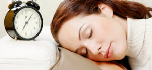 women sleeping next to alarm clock