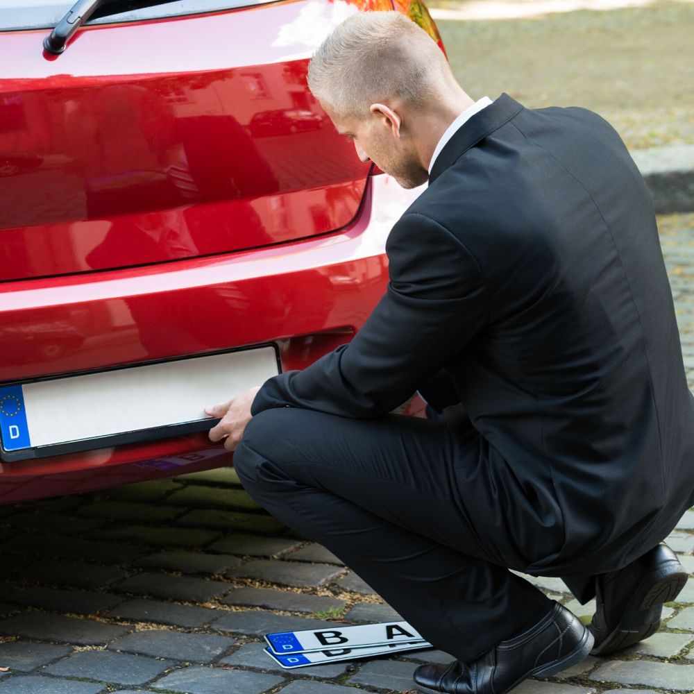 person changing a number plate on a car