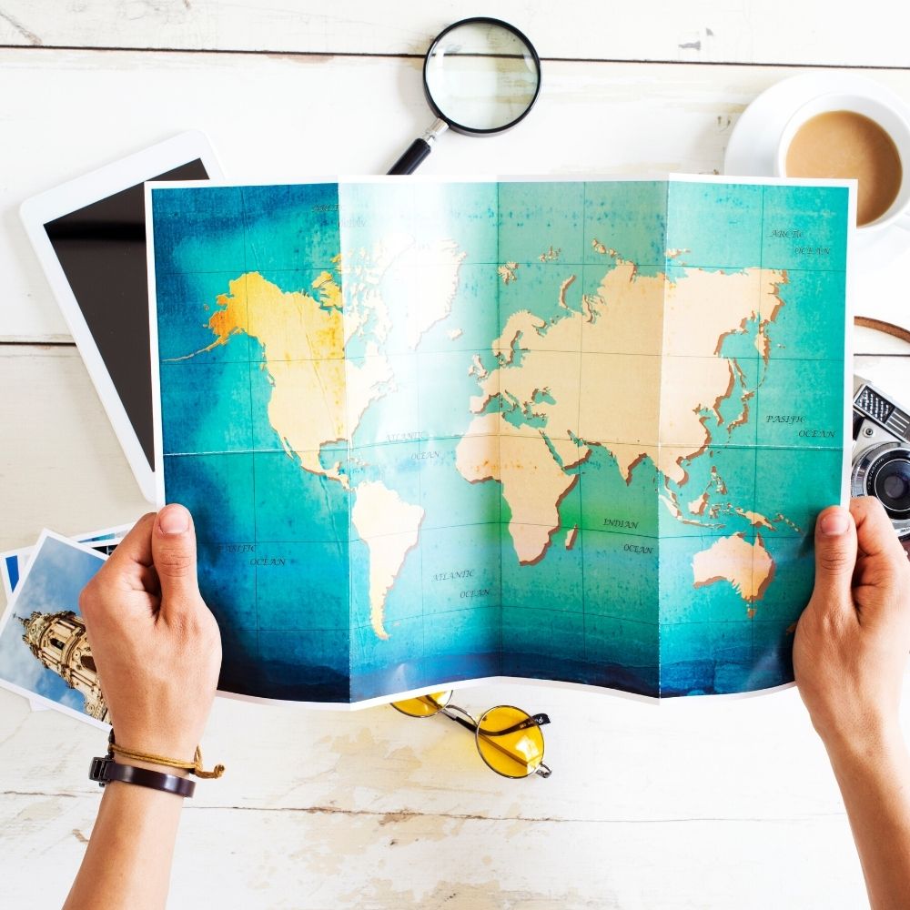 person holding a map of the world with coffee in the background