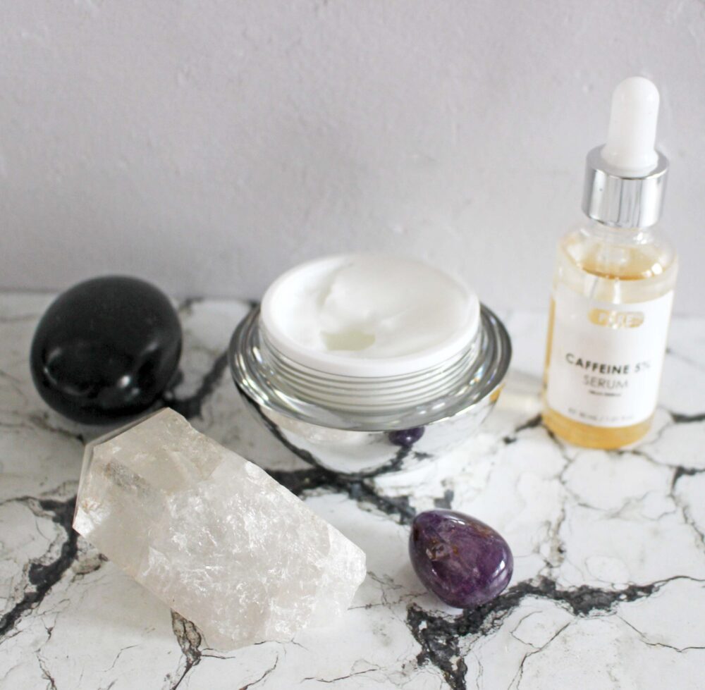 skinchemists products the Anti-Ageing Caviar Night Moisturiser on the right, it is in a silver reflective round tub the lid off, on the left the bi-phase caffeine serum bottle which contains a yellow liquid