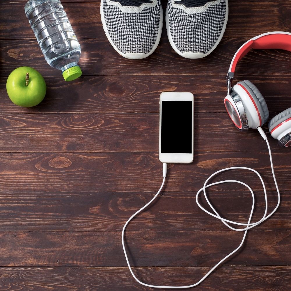 green apple, water, trainers and phone linked to headphones