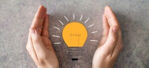 hands around the picture of a light bulb