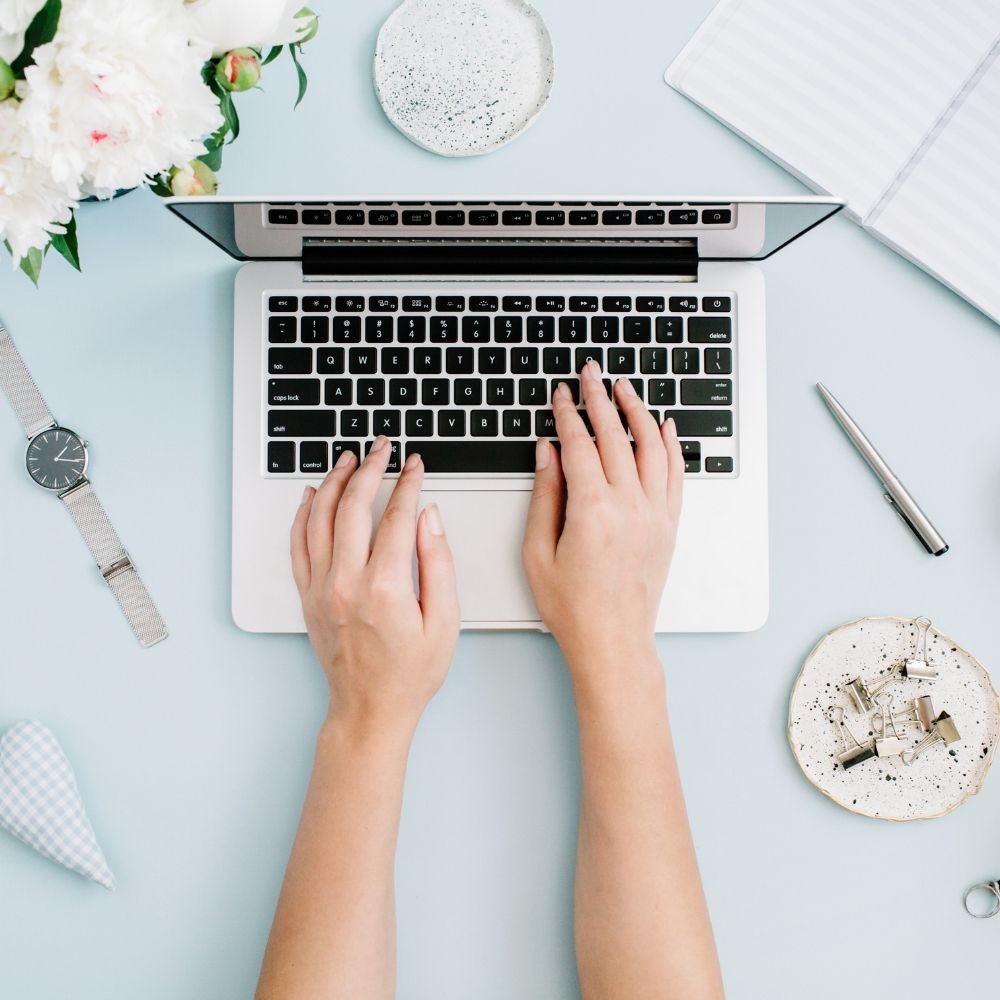 hands on a laptop with a blue background