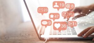 person at a computer with social icons showing