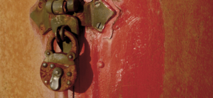 rusted round padlock on an old red door