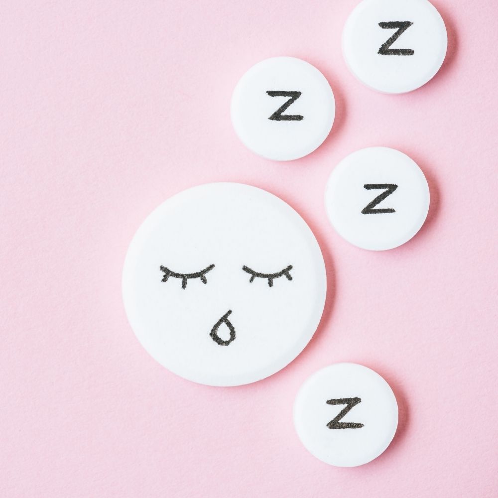 tired face and the letter z on white bubbles on a pink background