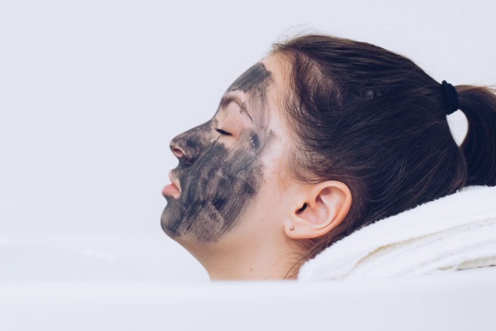 Young teenage girl relaxing with a face mask laying in a bathtub