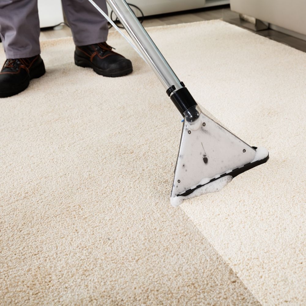 person cleaning a cream coloured carpet