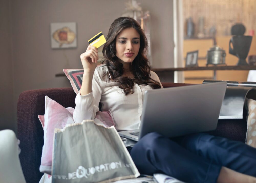 women holding a credit card on a silver laptop