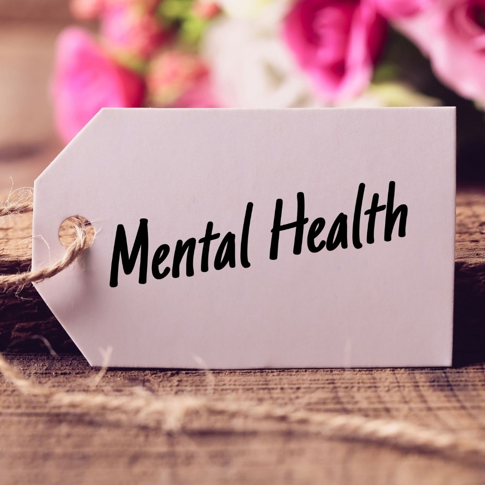 mental health written on a label with pink flowers in the back ground
