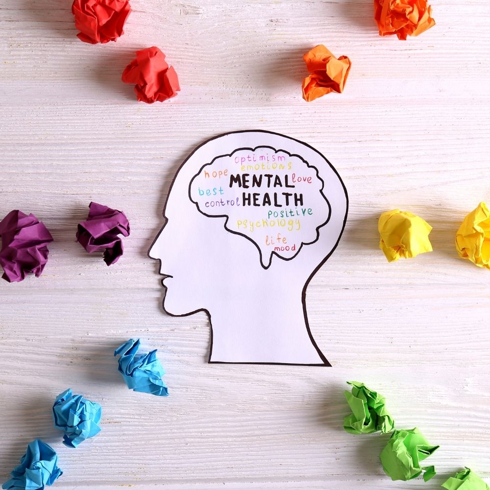 picture of a head with mental health written in the brain area, colours scrunched up paper around it