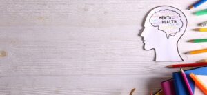 picture of a head with mental health written in the brain coloured pencil and books around