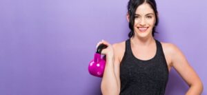 Women against purple background holding a kettle bell