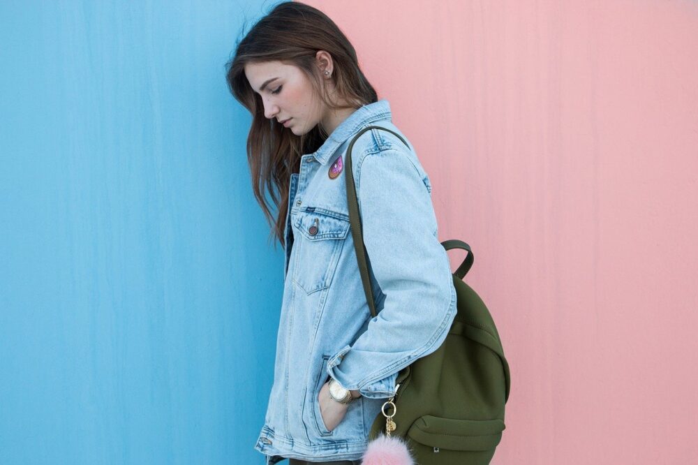 person wearing a blue denim jacket with black backpack
