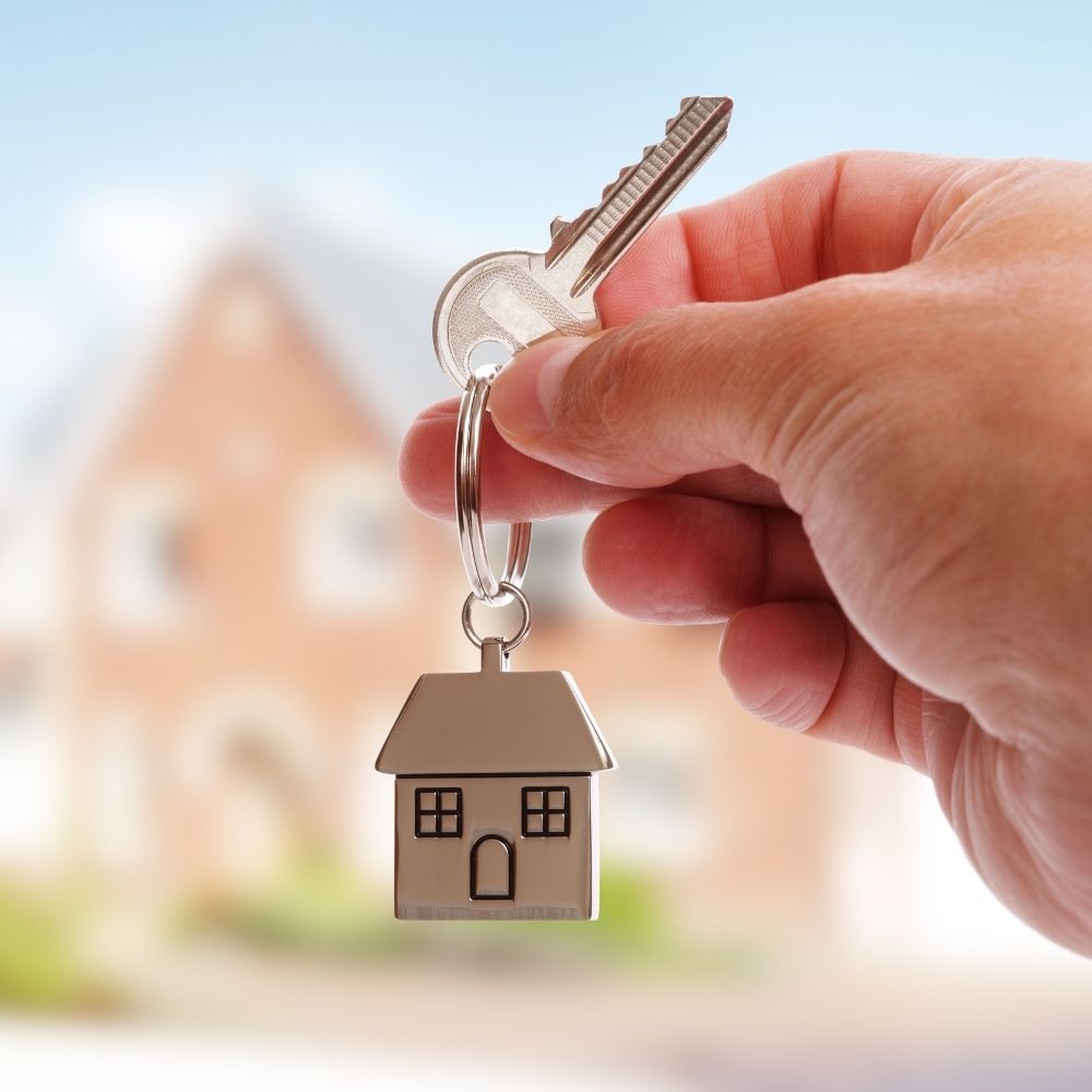 person holding a key with a keyring of a house