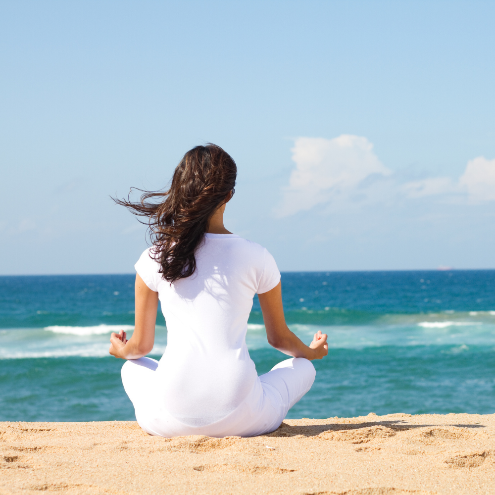 person practicing yoga or mediation at the beach