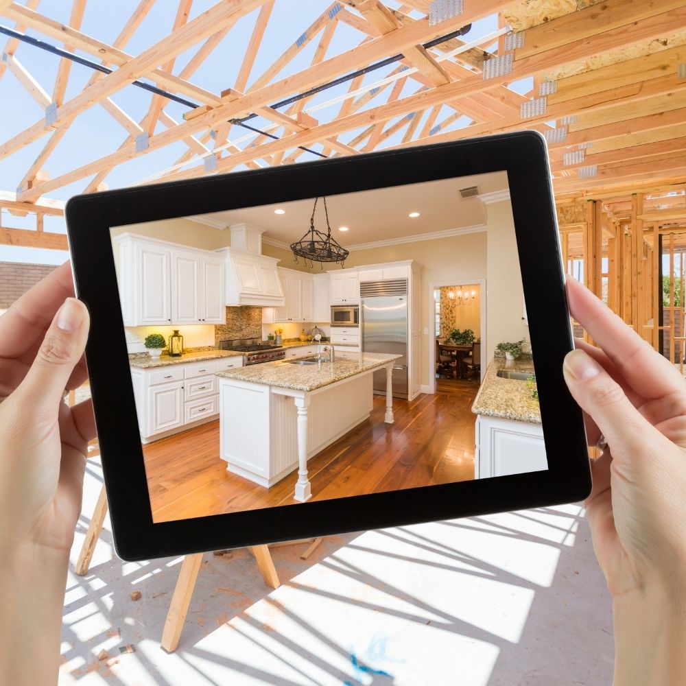 female holding a tablet with a finished kitchen design in front of a work in progress