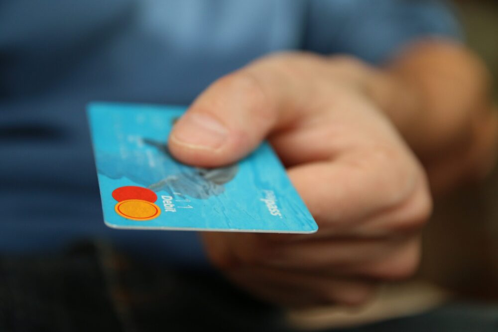 Person holding a credit or debit card which is blue in colour