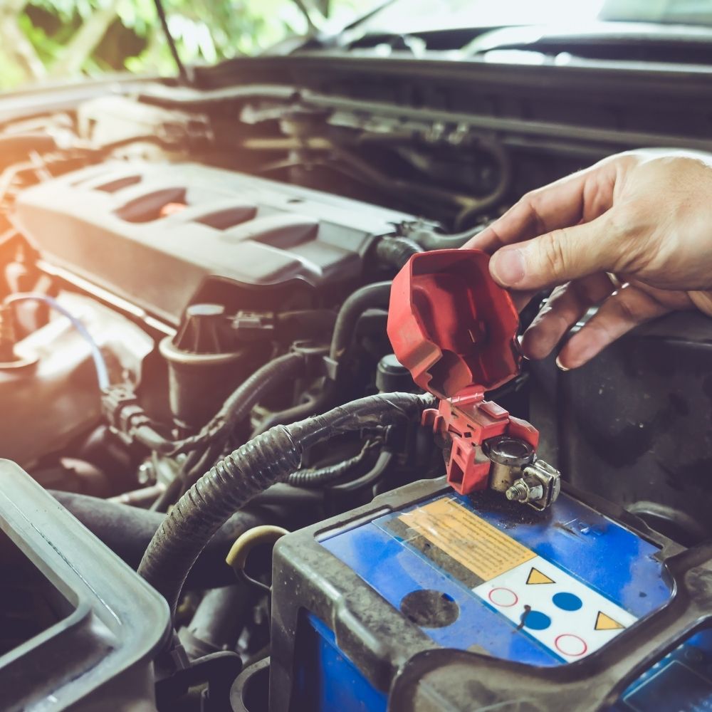 Hand of technician checking battery terminals and engine on the car