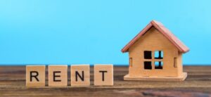 small house with rent written out in scrabble letters beside it