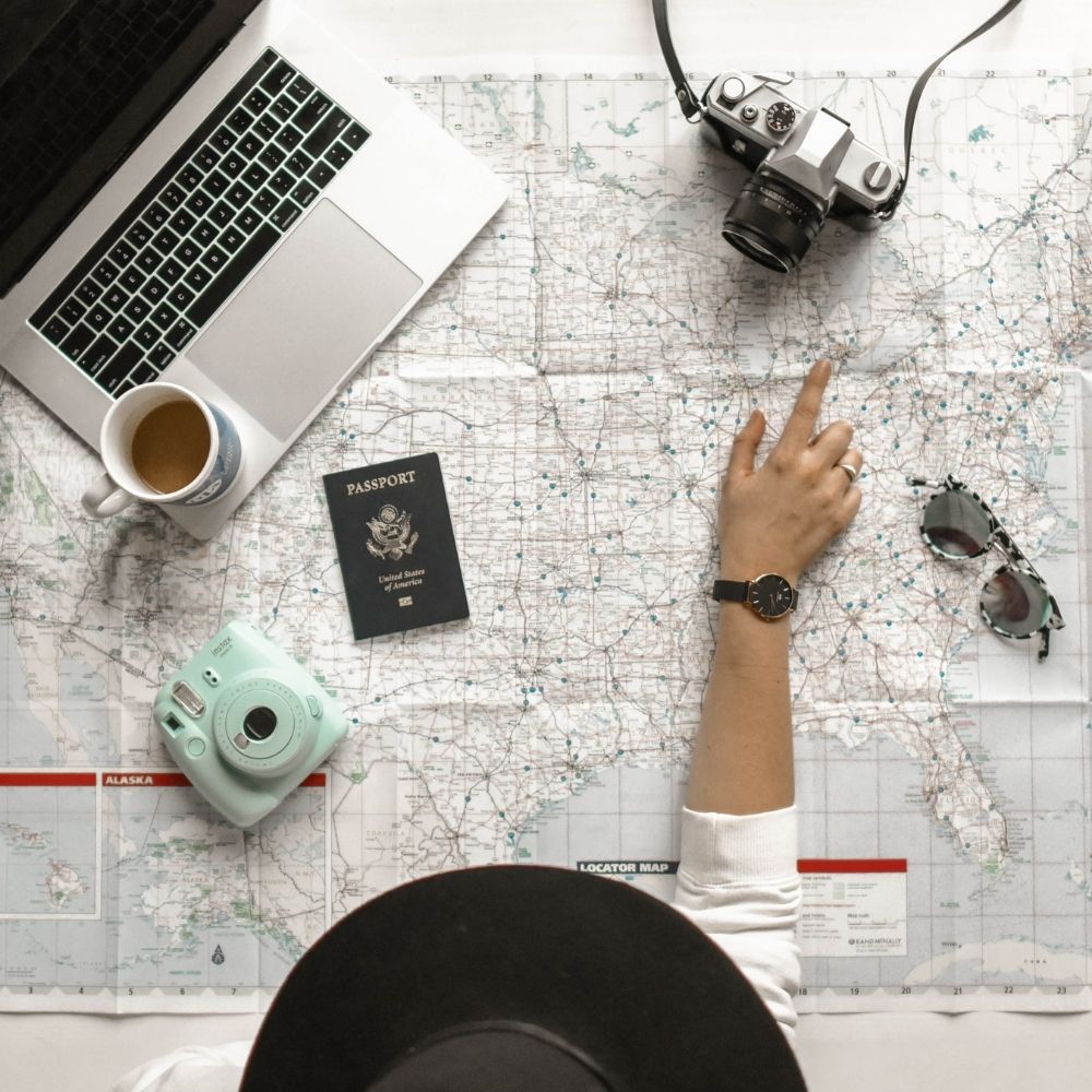 person pointing to a map with a coffee computer passport and other accessories around them