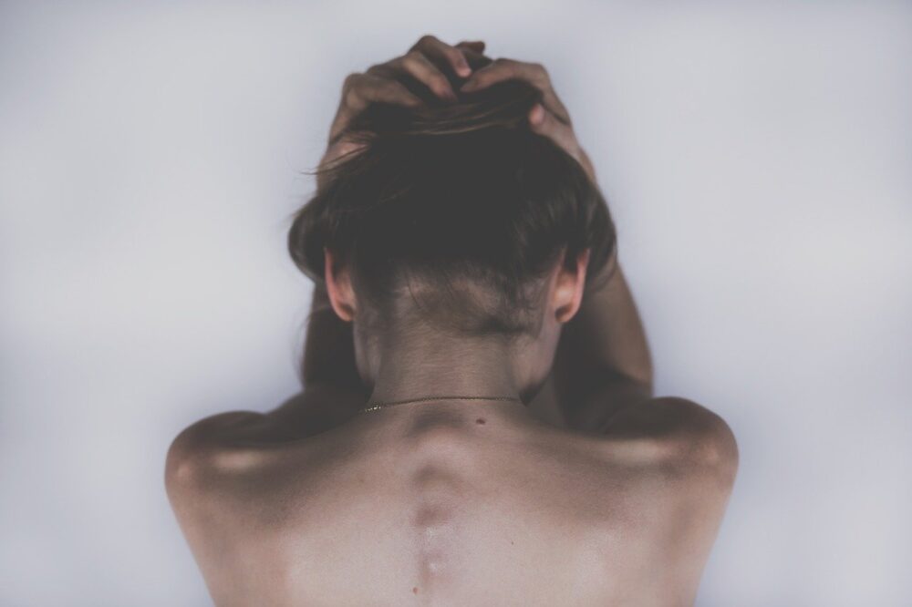 women holding her hair back with focus on her spin area