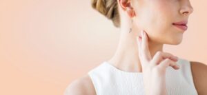 women against a peach background wearing a stunning pair of earrings