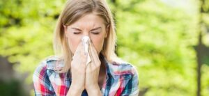 women holding a tissue to her nose suffering from an allergy