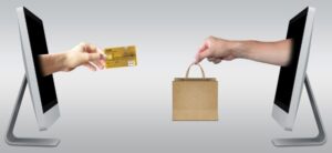 image of a hand coming out of a computer holding a credit card and another holding a bag