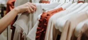 person picking up an item of clothing from a rack image licensed under CC0 via Canva Pro