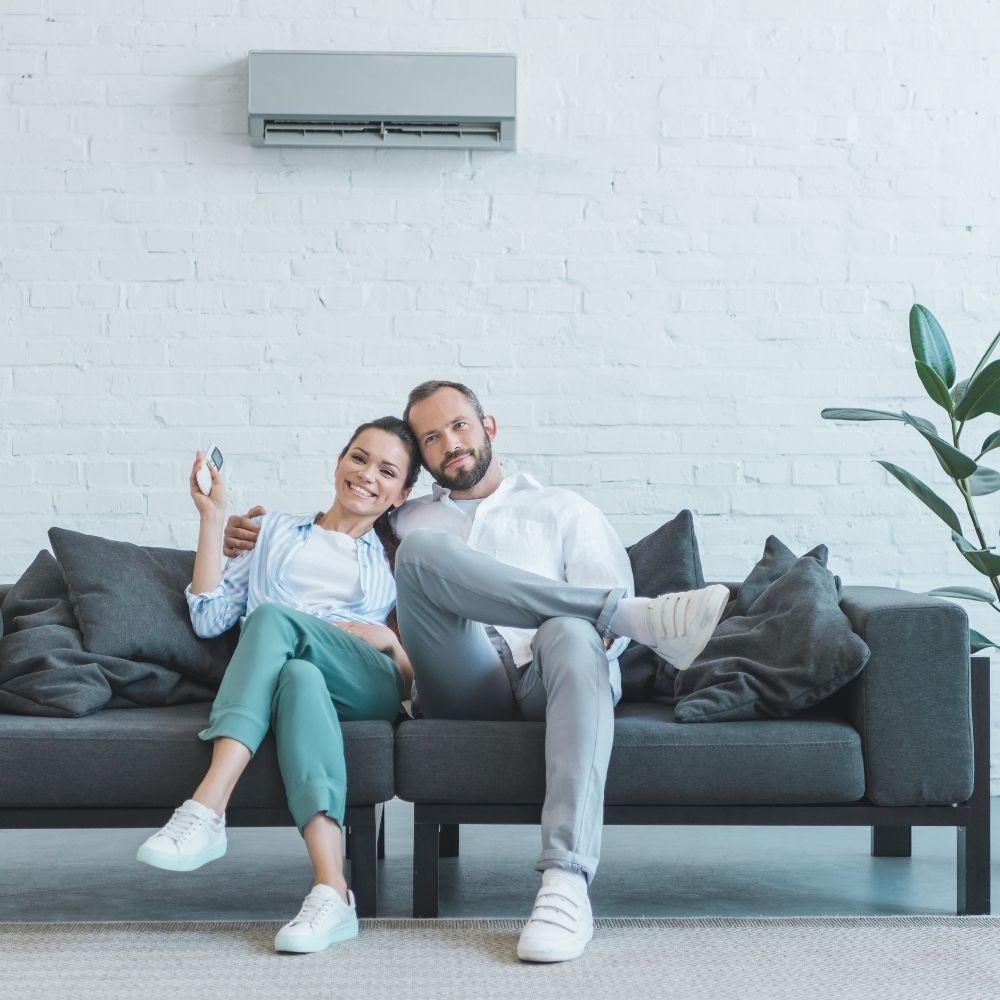 couple sat on a sofa under an air conditioning unit lab