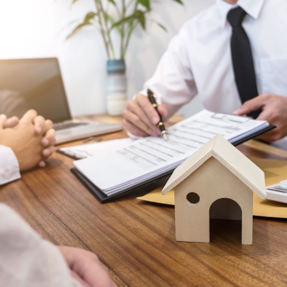 people sat doing paperwork with a small house