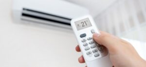 person adjusting the temperature on an air conditioning unit