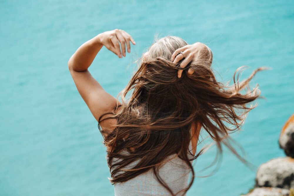 women sat by a pool tossing her hair back