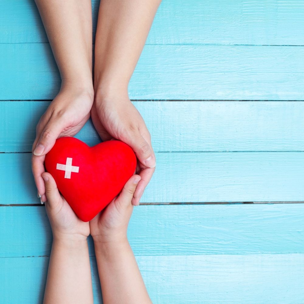 two people holding a red heart on a blue backdrop