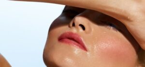 woman shielding her eyes from the sun with glowing skin