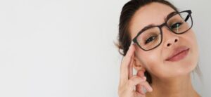 women wearing glasses smiling and touching them