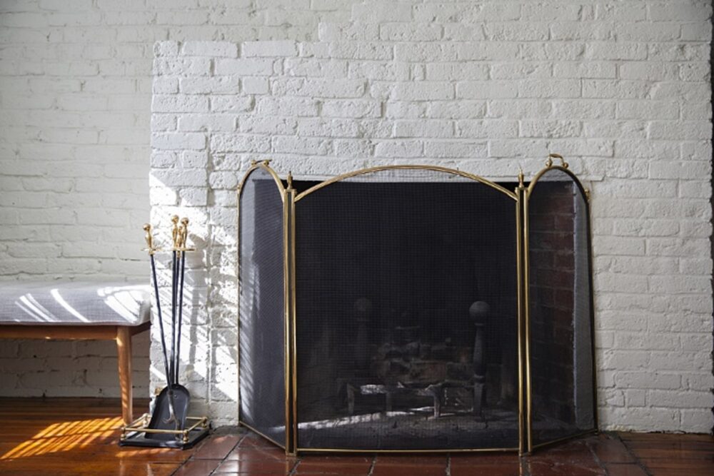 Fireplace in a room with tools beside it.