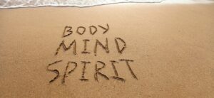 body mind spirit written on the sand at the seas edge