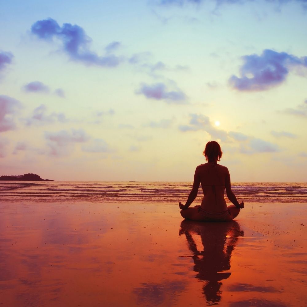 person sat meditating during sunset