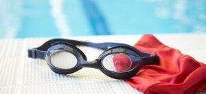 swimming goggles and a hat by the side of a pool