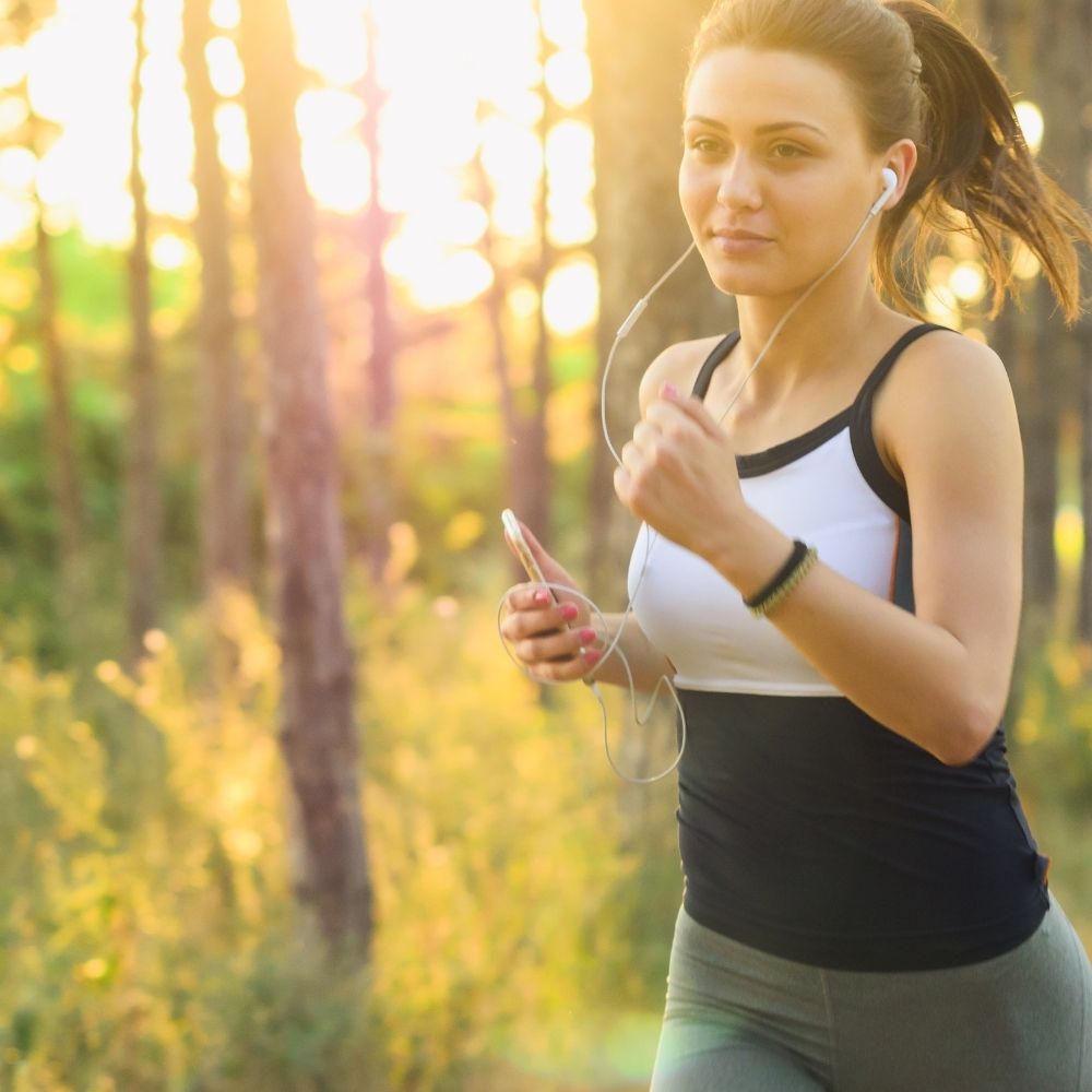 women wearing earphones and jogging in a forest