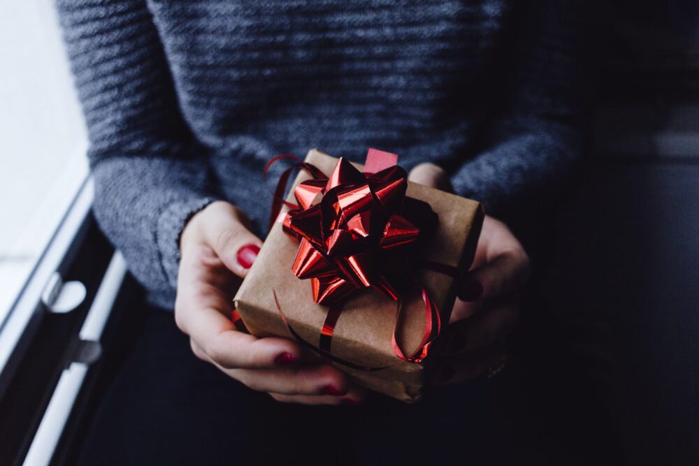 Lady holding a package tied up with a red ribbon