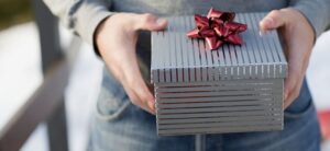 person holding a silver box with a red bow