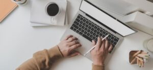 person walking on a laptop with a cup of coffee
