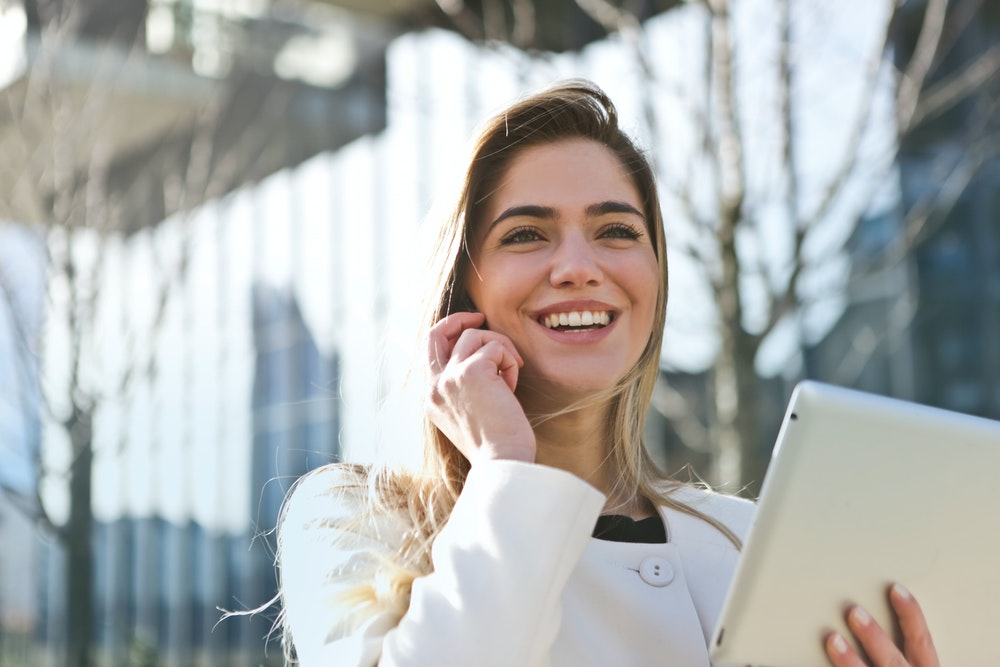 women in a white blazer holding a tablet computer