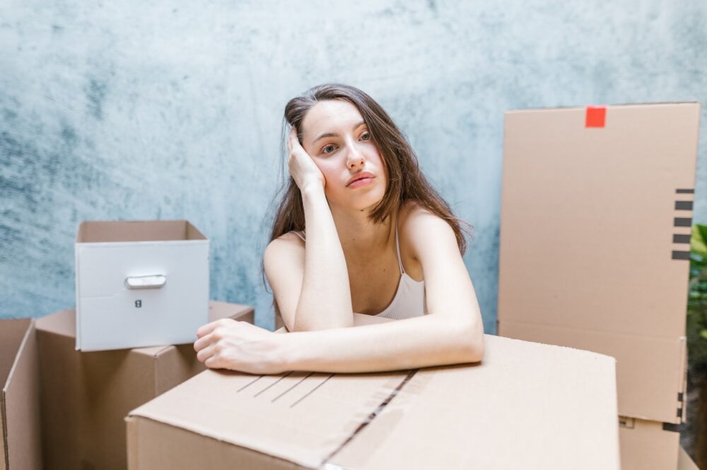 Woman surrounded by packing boxes looking stressed