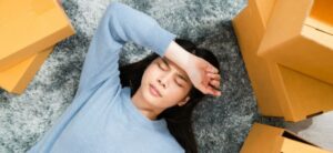 woman surrounded by boxes with a hand over her forehead