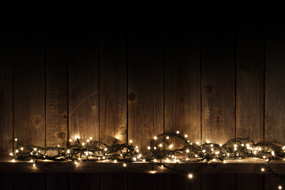 Christmas lights on shelf in front of wooden wall with copy space