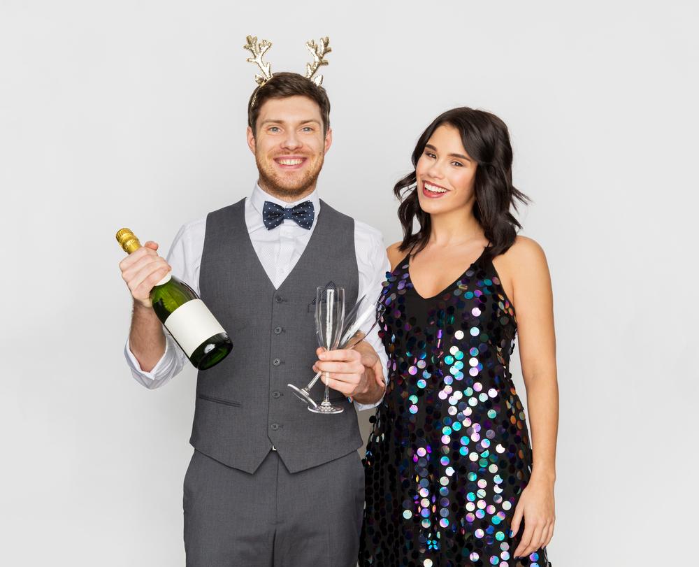 celebration, people and holidays concept - happy couple with bottle of non alcoholic champagne and wine glasses at christmas or new year party